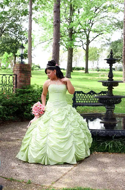 Young hispanic teen wearing a lime green quinceanera dress on her 15th birthday.