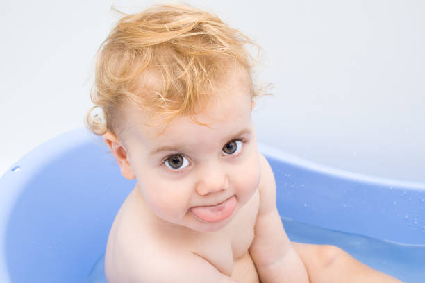 Baby girl showing her tongue in a bath stock photo