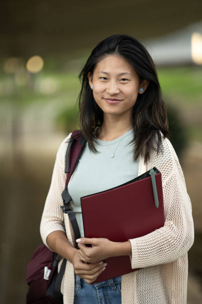 istock Handsome satisfied student holding a notebook looking at camera.Relaxed and happy woman standing outside with folder in her hands. 1738689126