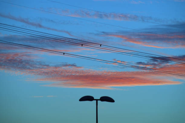 Electric cable and street lamp against sunset sky