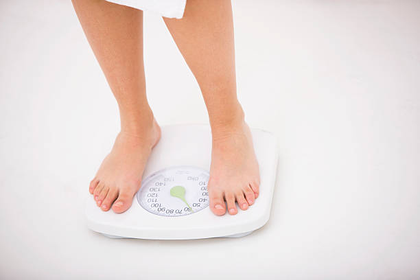 istock Woman standing on weight scale 173870570