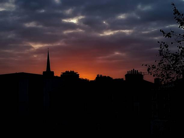istock Silhouette of rooftops over a cloudy sky at sunrise. 1738711271
