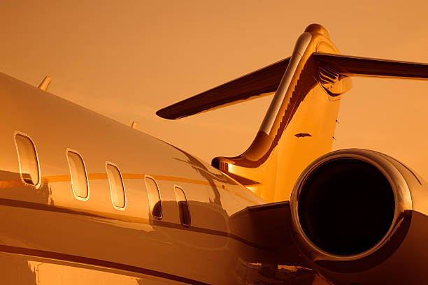 corporate jet sotto luce arancione tramonto - wing airplane window sunset foto e immagini stock