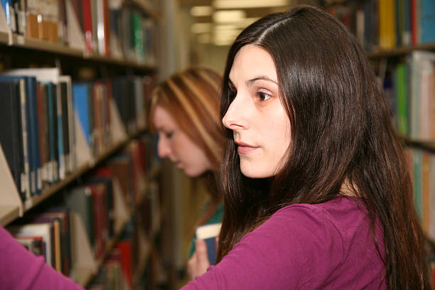 istock Female College Students Looking Through Library Books 173871743
