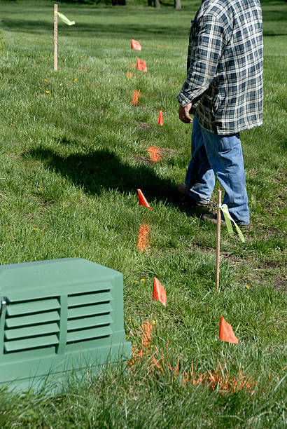 Marking Buried Cables in Back Yard A utility technician marks paths and boundaries of buried electronic cables next to a junction box. yard measurement stock pictures, royalty-free photos & images
