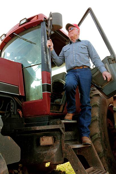 Farmer getting out of his big red tractor. Vertical image good for agriculture use.