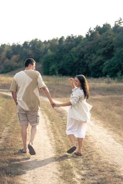 istock A man and a woman walk into a field holding hands. 1738722890
