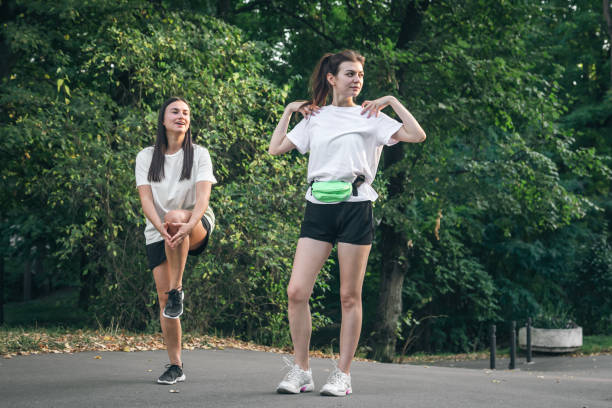 istock Two young women do exercises to warm up their muscles before jogging. 1738740670