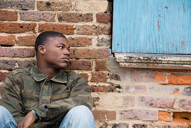 Homeless African American Teen Boy "A photograph of a homeless street kid, African American teenager sitting against a brick wall in an urban city." runaway stock pictures, royalty-free photos & images