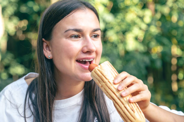 istock A young woman eats a hot dog on a cafe terrace. 1738744244