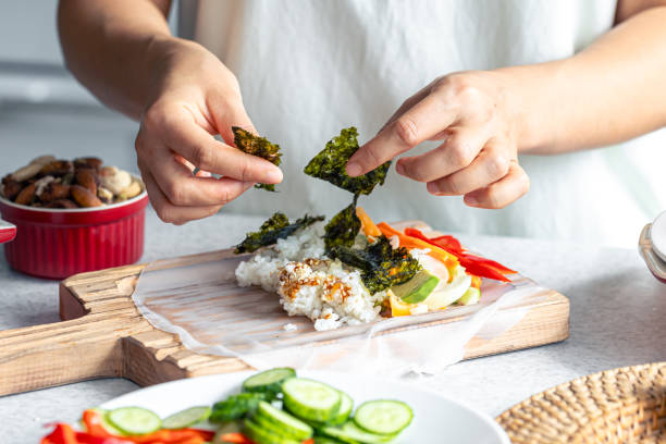 istock Woman preparing spring rolls in rice paper on kitchen table. 1738753775