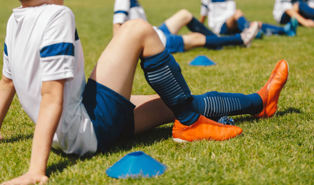 groupe de jeunes garçons sur une séance d’étirement en plein air avec des rouleaux en mousse. joueurs de football d’une équipe en entraînement physique pour soulager la tension musculaire, la douleur et l’inflammation - foot massage photos et images de collection