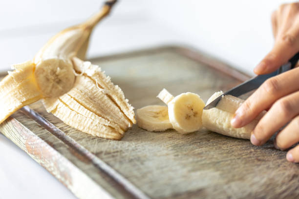 istock A woman cuts a banana on a cutting board. 1738762259