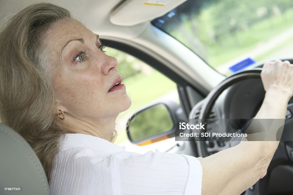 Starszy Dorosły kobieta kontroli jej lusterko wsteczne podczas jazdy - Zbiór zdjęć royalty-free (60-69 lat)