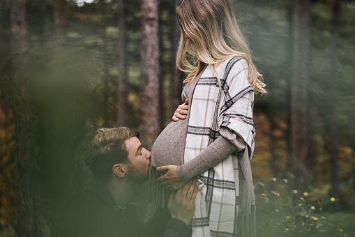 Happy couple enjoying nature. Woman is pregnant, babies coming soon.