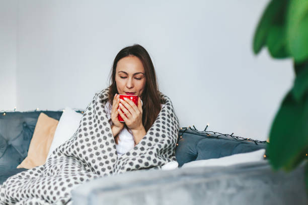istock Woman enjoying her time on the couch with a cup and a warm blanket 1738776413