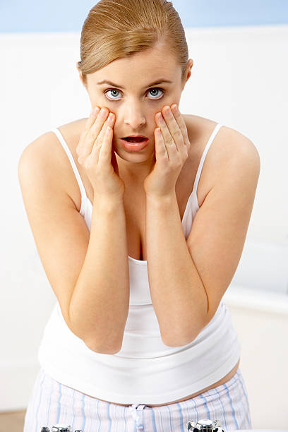 Woman Looking At Reflection In Bathroom stock photo