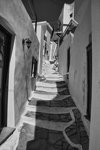 A narrow alley lined with buildings, in grayscale