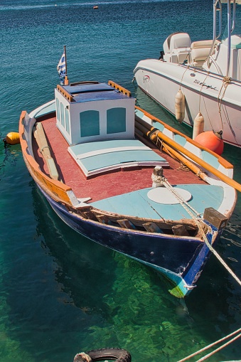 A boat securely moored at a pier, its mooring ropes fastened to dockside cleats
