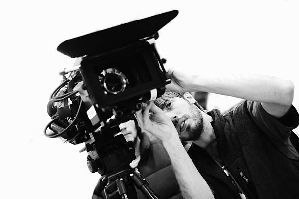 istock Black-and-white angled young man adjusting a movie camera 173879920