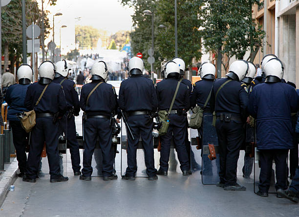 Riot police "A line of riot police observing a protest march in Athens, Greece.In the same series:" strike protest action stock pictures, royalty-free photos & images