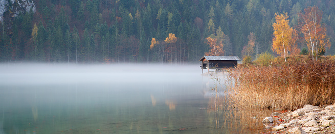 Mountain lake with fishing hut in autumn