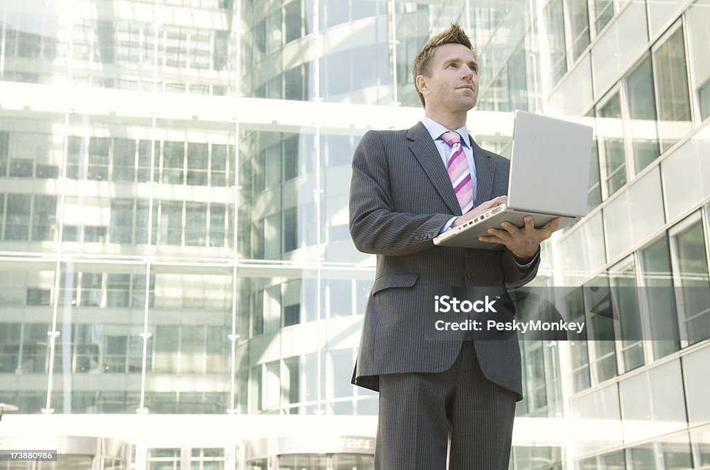 Бизнесмен, стоя на современное Офисное здание, работающих на ноутбуке - Стоковые фото 30-39 лет роялти-фри