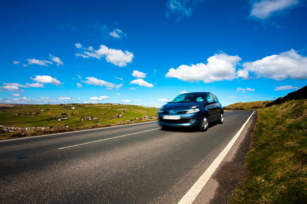 Car on a country road A car speeds by on a country road. west yorkshire stock pictures, royalty-free photos & images
