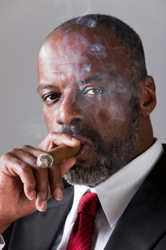 Man smoking a pipe on dark background. Profile portrait.
