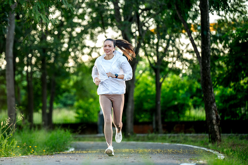 Fitness runner girl in public park. healthy lifestyle and wellness being concept,Fit young Asian woman jogging in park smiling happy running and enjoying a healthy outdoor lifestyle. Wellness being concept