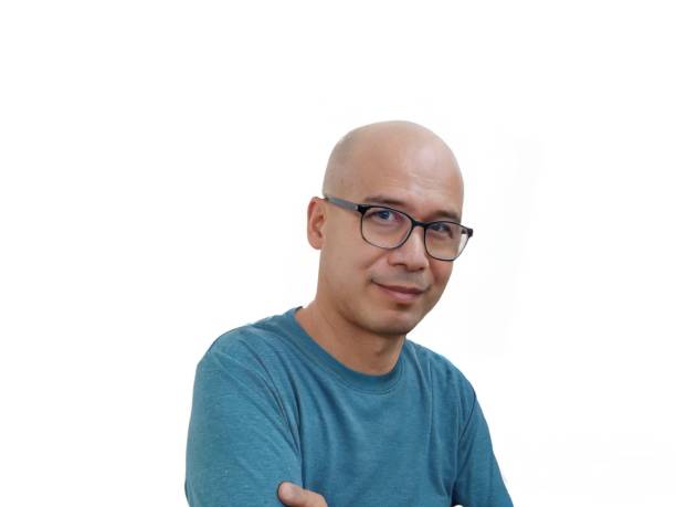 a completely bald, bespectacled man wears a green round-neck t-shirt. - completely bald fotos imagens e fotografias de stock