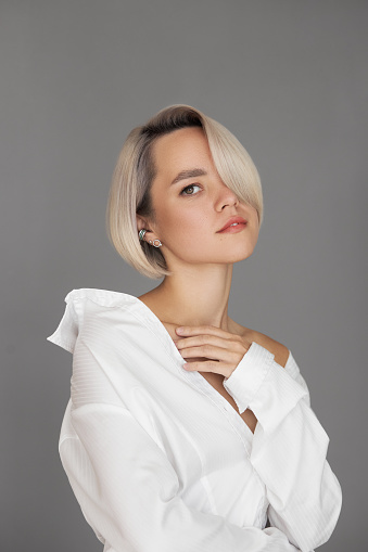 Blonde woman with short dyed hair, short haircut. Hair root care, woman in shirt fashion portrait