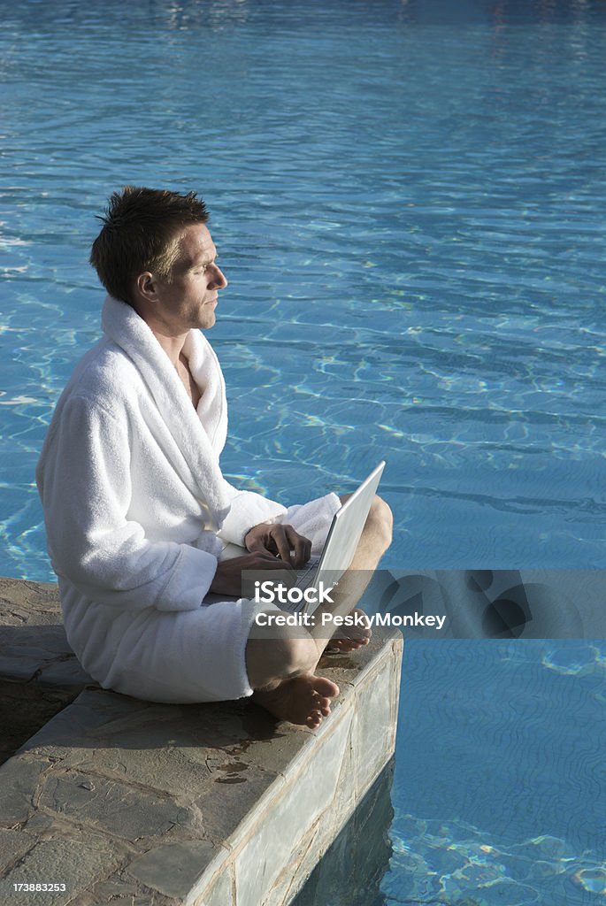 Guy dans la Robe se trouve au bord de la piscine avec son ordinateur portable - Photo de Activités de week-end libre de droits