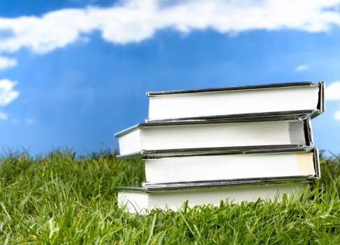 pile of books waiting to be read lying on grass