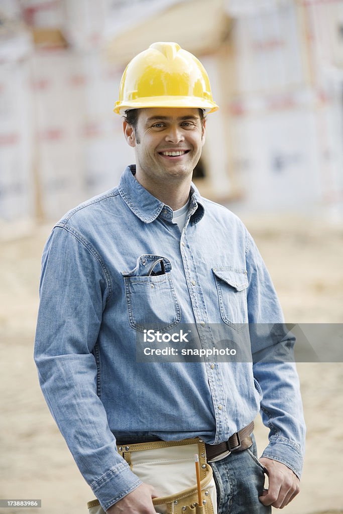 Construcción hombre que agarra Blueprints usando cascos - Foto de stock de Accesorio de cabeza libre de derechos