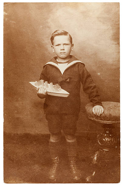 Vintage Portrait of Boy with Toy Boat Vintage sepia toned portrait of a young boy wearing a sailor's outfit holding a toy boat. Some dust and scratches which convey age of original image. Circa 1910. edwardian style photos stock pictures, royalty-free photos & images