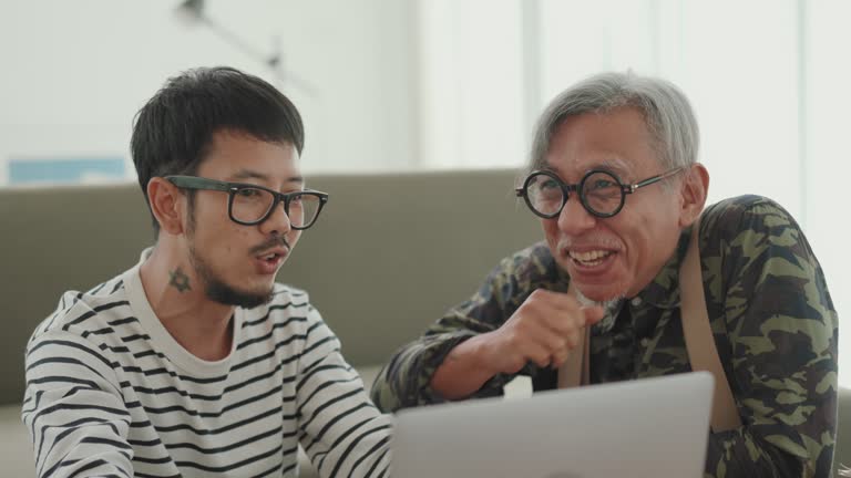 Multigenerational Bonding: Asian Man Working from Home, Sharing a Smile and Conversation with His Senior Father.