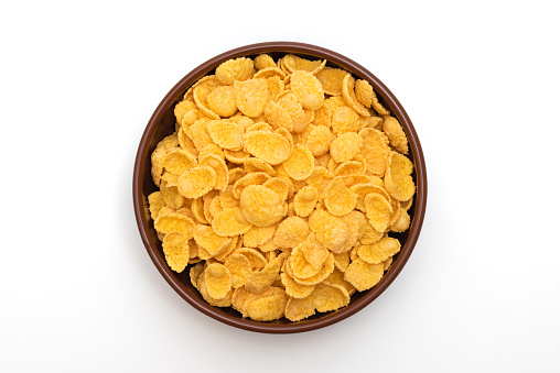 A plate of corn flakes in a plate on a white background. Top view