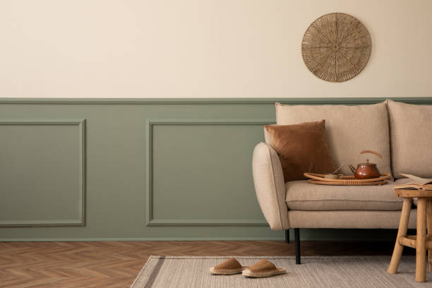 istock Creative composition of living room interior with copy space, beige sofa, green wall with stucco, wooden coffee table, brown slippers, gray plaid and personal accessories. Home decor. Template. 1738863608