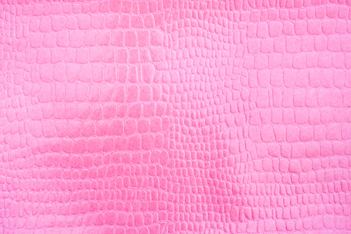 Pink textured snakeskin paper photographed close-up revealing details of the paper as well as the pattern