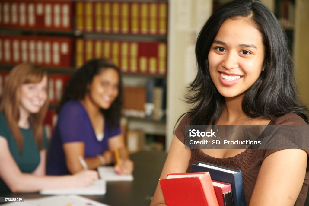 Uśmiechnięta kobieta studenta gospodarstwa książki i z pozostałymi uczestnikami szkolenia - Zbiór zdjęć royalty-free (18-19 lat)