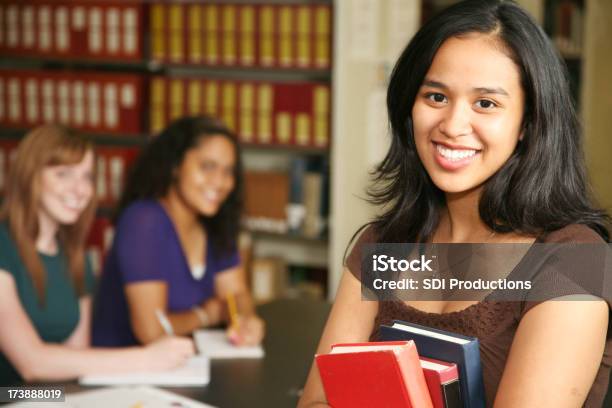 Foto de Sorrindo Feminino Estudante Segurando Livros E Com Os Seus Colegas De Turma Com Facilidade e mais fotos de stock de 18-19 Anos