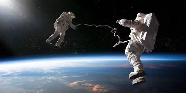 Photo of Two Astronauts On Tethered Spacewalk Facing Each Other