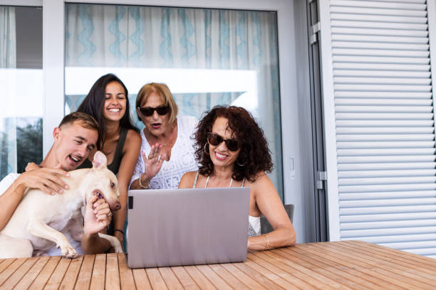 familia caucásica con su perro están en la terraza de su casa usando la computadora portátil durante una videollamada - family pets dog multi generation family fotografías e imágenes de stock