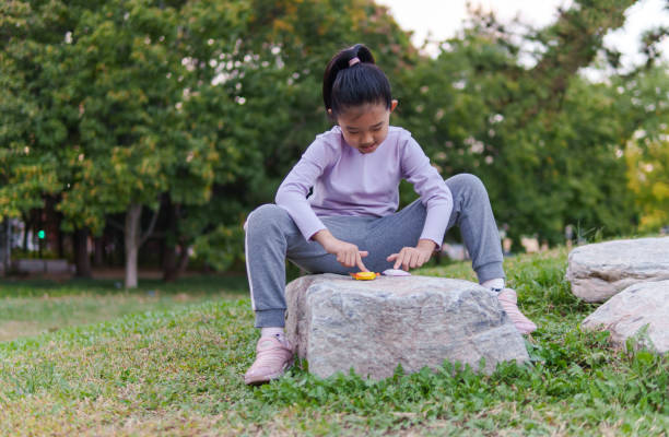 Beautiful happy girl with long hair in pink shirt playing in public park.