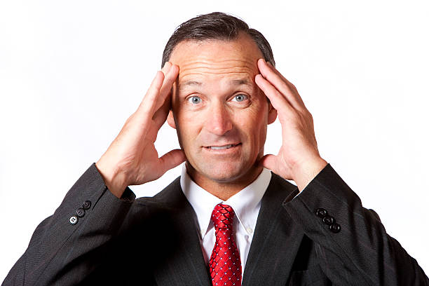 portrait of a 40-45 year old caucasian businessman with his hands to his head and a stressed out look on his face. isolated on a white background