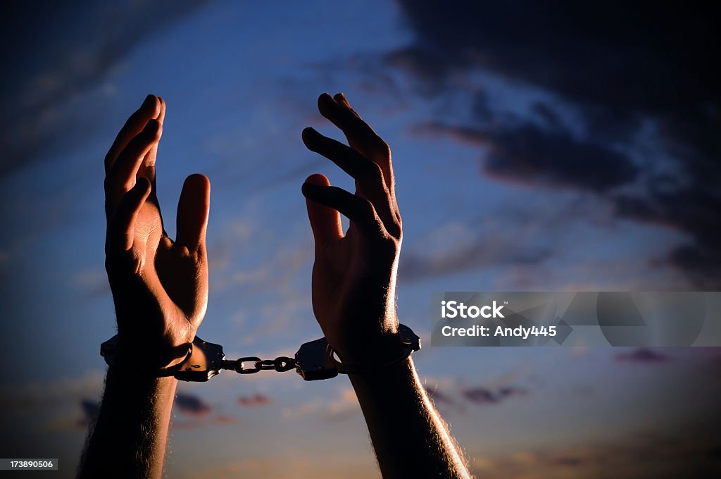 Closeup image of hands with handcuffs lifted in despair Man's hands with handcuffs on outstretched to the sky. Arms Outstretched Stock Photo