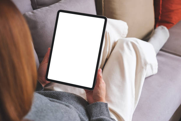 istock Mockup image of a woman holding digital tablet with blank desktop screen while lying on a sofa at home 1738908039