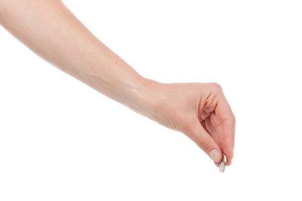 A hand holding a coin as if inserting it into something.