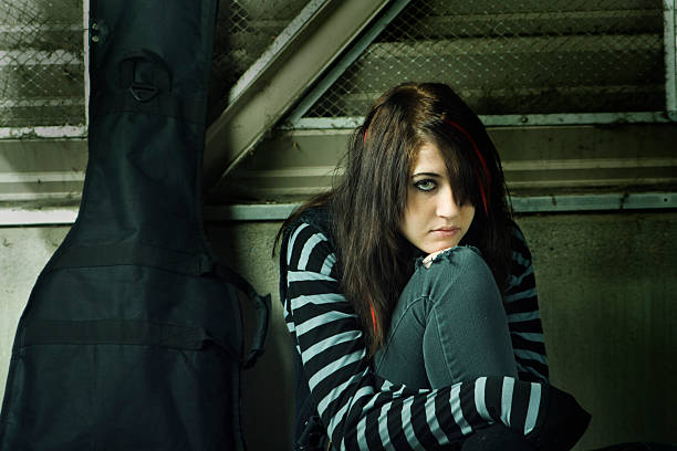 Young Street Musician Subject: Young teen goth street musician in the evening. black hair emo girl stock pictures, royalty-free photos & images